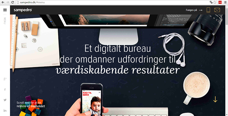 A website screenshot showing the homepage of Sampedro, a digital agency, featuring a desktop monitor, camera lens, smartphone, headphones, and a cup of coffee arranged on a dark desk.