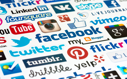 A close-up image showing a colorful collage of various popular social media platform logotypes and icons, including Facebook, Twitter, YouTube, and Instagram.