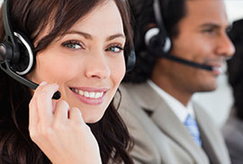A smiling customer service representative wearing a headset and handling online inquiries in a call center.