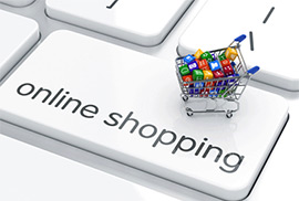 A small shopping cart filled with colorful blocks sits on a computer keyboard with the key reading online shopping.