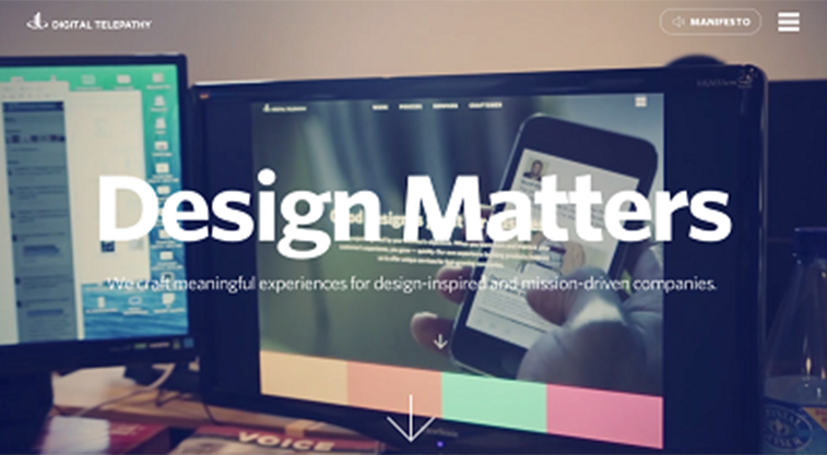 Computer monitors display a website with the words "Design Matters" and a hand holding a smartphone on the screen.