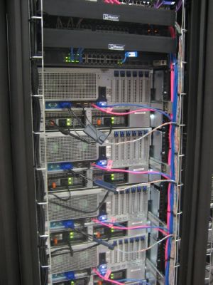A server rack filled with multiple mounted servers, network switches, and neatly organized cables connected to the front panels.