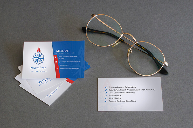 A stack of NorthStar Advisors Group business cards and a pair of round glasses sit on a gray surface, with one card flipped to show its services.