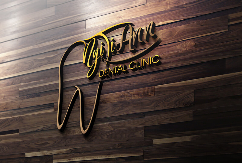 The gold 3D logo for Ngi-Ji Ann Dental Clinic, shaped like a stylized tooth, is mounted on a dark wooden plank wall.