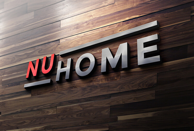 3D metal and red logo reading "NU HOME" mounted on a dark wooden plank wall.
