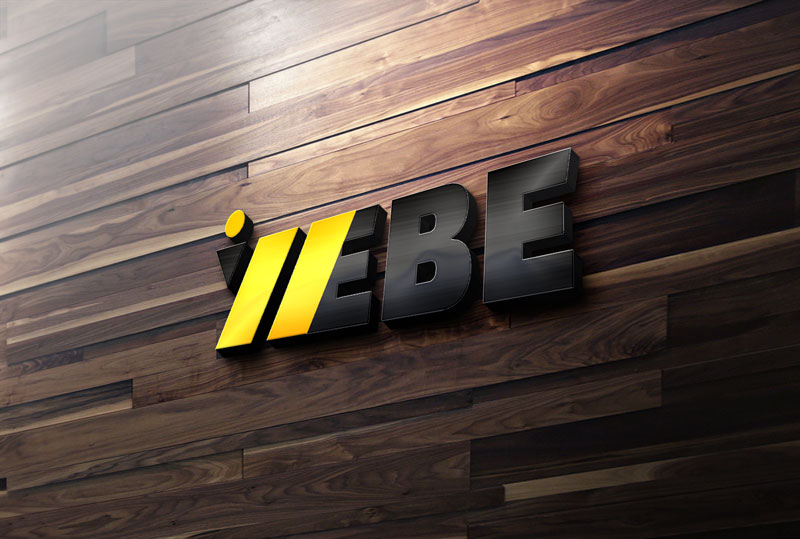 A 3D company logo that reads BE with two yellow diagonal stripes is mounted on a dark wood panel wall.
