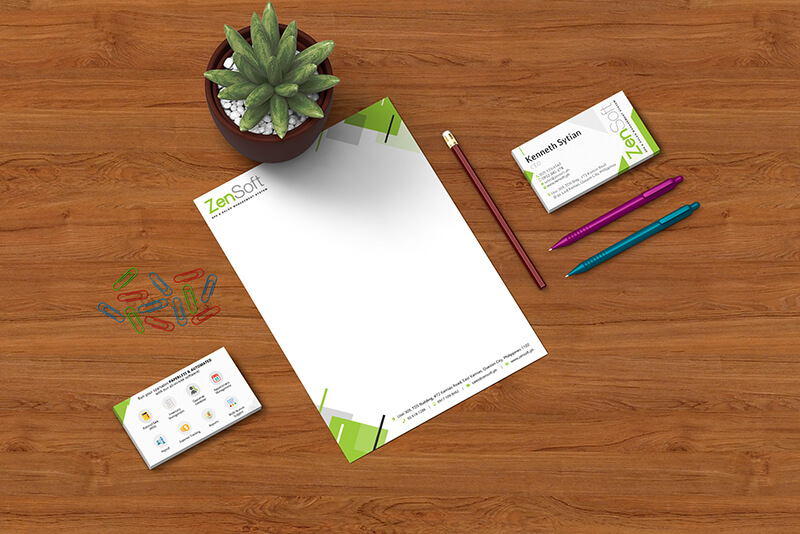 Overhead shot of a ZenSoft letterhead with a business card, pen, pencils, and a small potted succulent on a wooden desk.