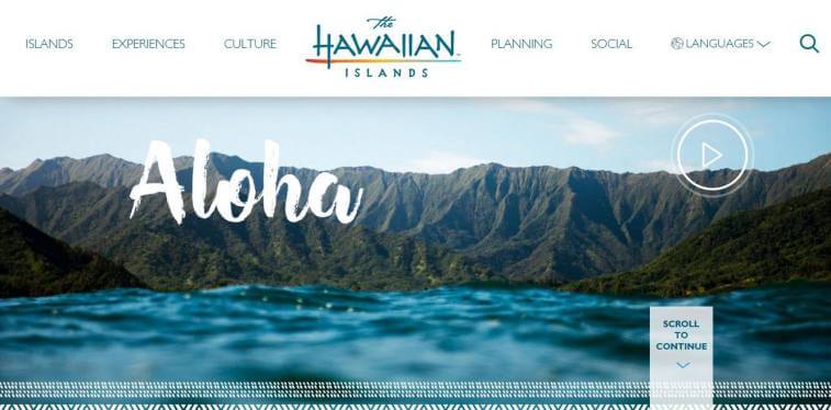 A screenshot of The Hawaiian Islands website featuring a video banner with the word Aloha overlaid on a view of green mountains and blue water.