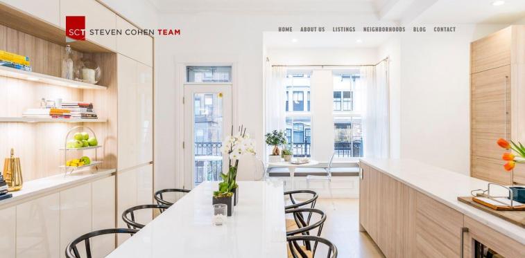 Website screenshot of Steven Cohen Team displaying a bright, modern dining and kitchen area with light wood cabinetry and a white dining table.