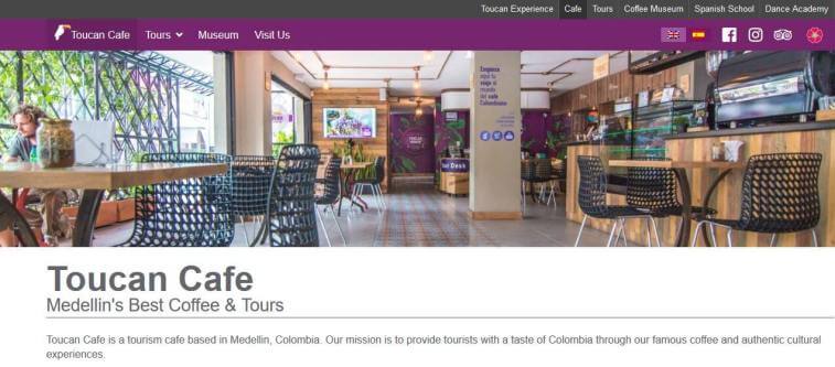 Website screenshot of Toucan Cafe in Medellin, Colombia, showing its modern interior with tables, chairs, and a coffee bar.