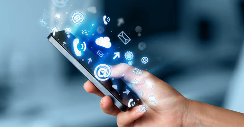 A hand holds a smartphone with glowing blue icons for calls, emails, clouds, and data floating out of it.
