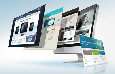 Multiple website design layouts and pages floating in front of computer monitors, illustrating website design and development.